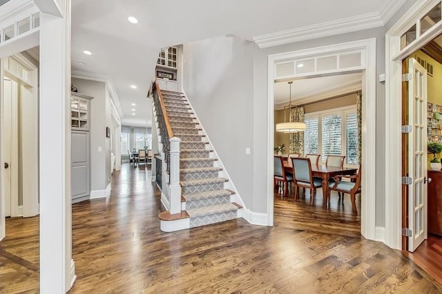 entrance foyer with crown molding and dark wood-type flooring