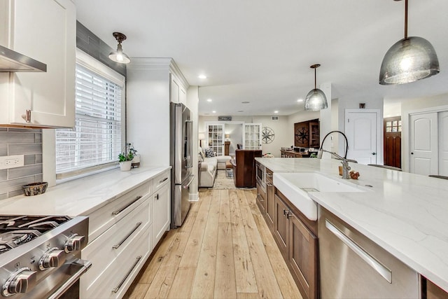 kitchen featuring white cabinetry, appliances with stainless steel finishes, sink, and hanging light fixtures