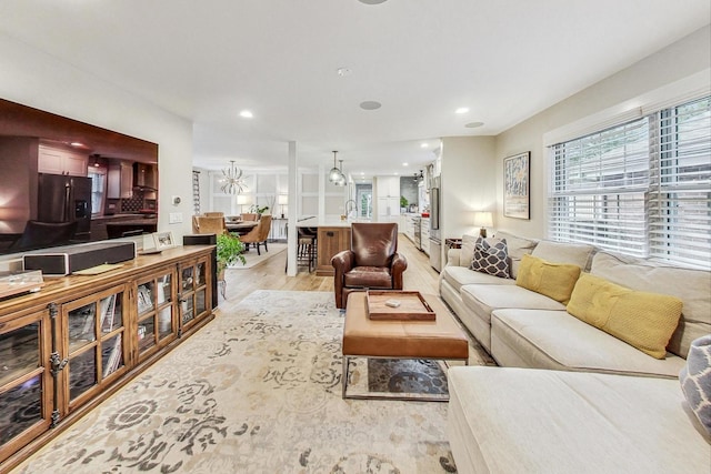 living room featuring sink, light hardwood / wood-style flooring, and a notable chandelier