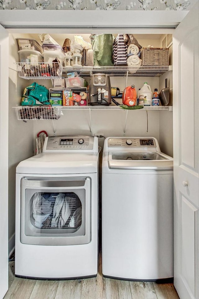 clothes washing area with separate washer and dryer and light hardwood / wood-style floors