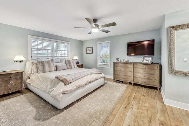 bedroom with ceiling fan, multiple windows, and light wood-type flooring