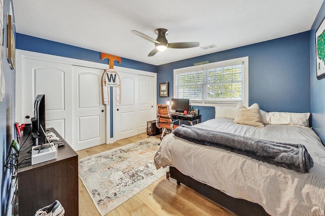 bedroom featuring ceiling fan, two closets, and light wood-type flooring