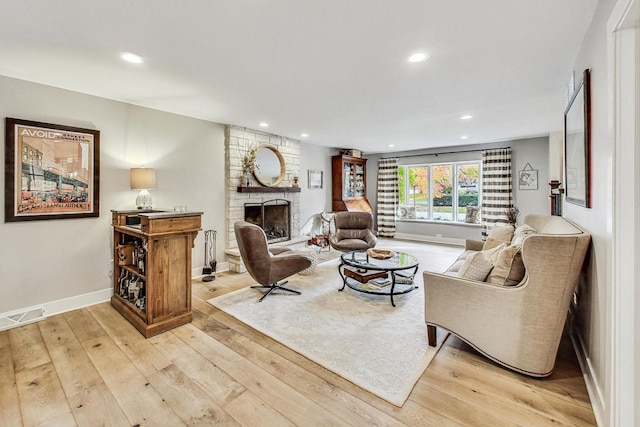 living room with a large fireplace and light hardwood / wood-style flooring