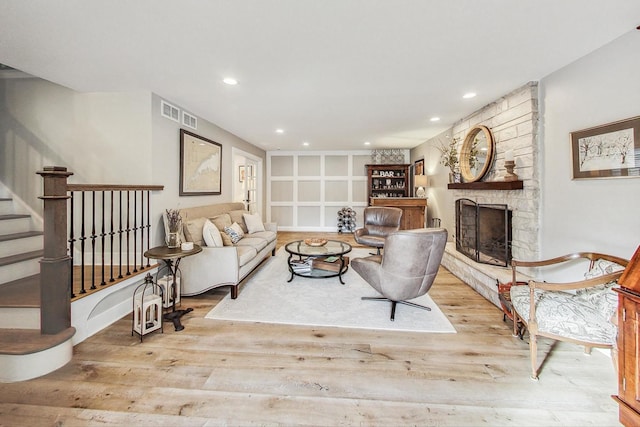 living room with a stone fireplace and light hardwood / wood-style flooring