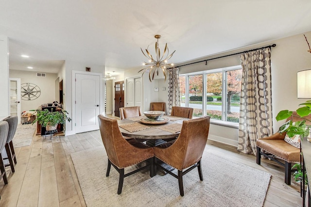 dining room with light wood-type flooring and an inviting chandelier