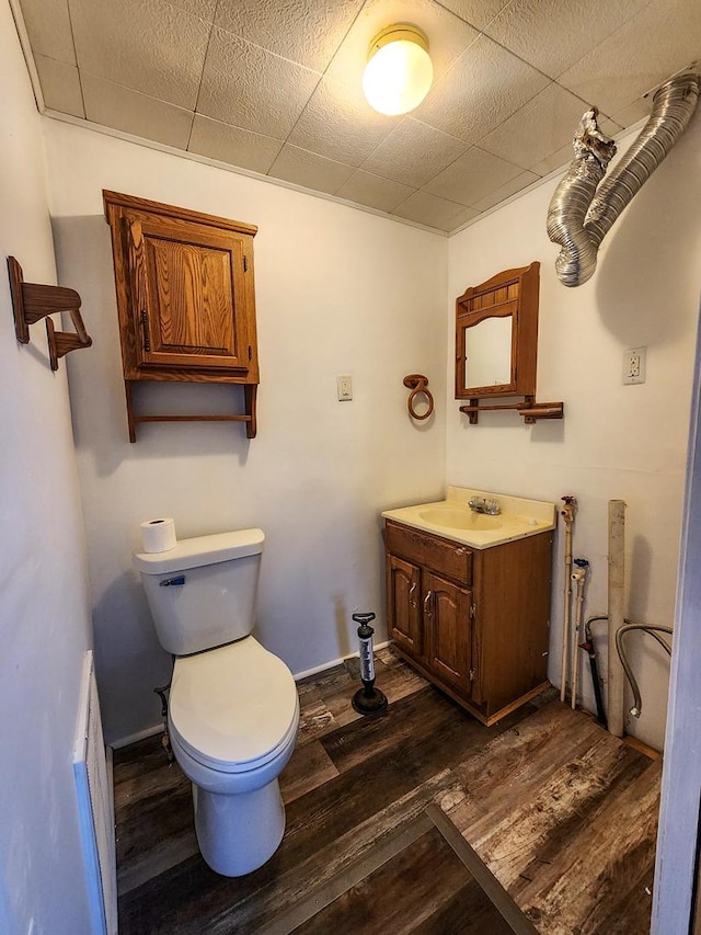 bathroom with vanity, hardwood / wood-style floors, a paneled ceiling, and toilet