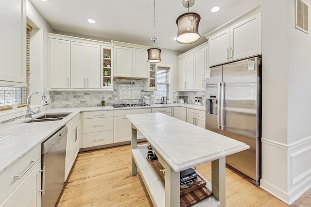 kitchen featuring hanging light fixtures, appliances with stainless steel finishes, sink, and white cabinets