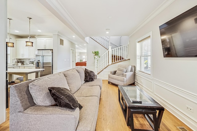 living room with crown molding and light hardwood / wood-style flooring