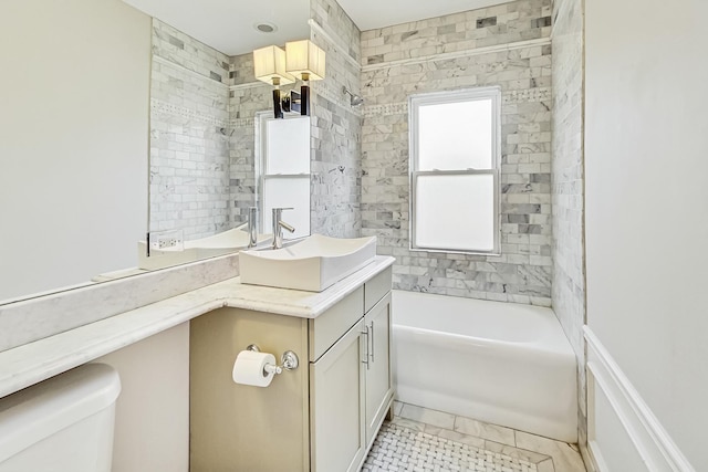 full bathroom featuring vanity, tiled shower / bath, and toilet