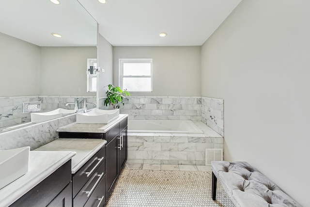 bathroom with vanity, a relaxing tiled tub, and tile patterned floors