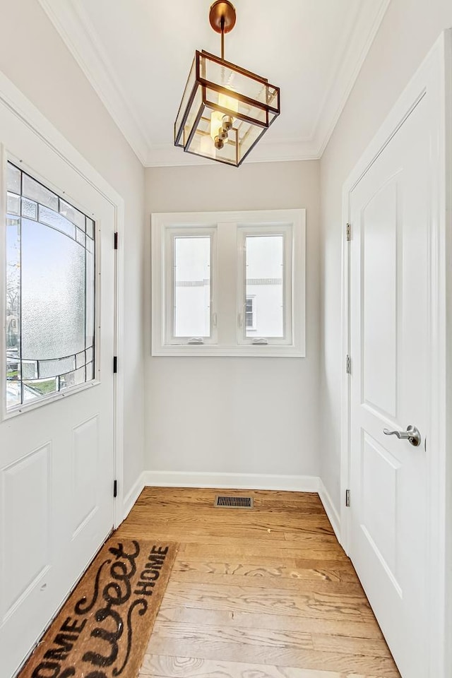 doorway to outside featuring crown molding, a wealth of natural light, and light hardwood / wood-style floors