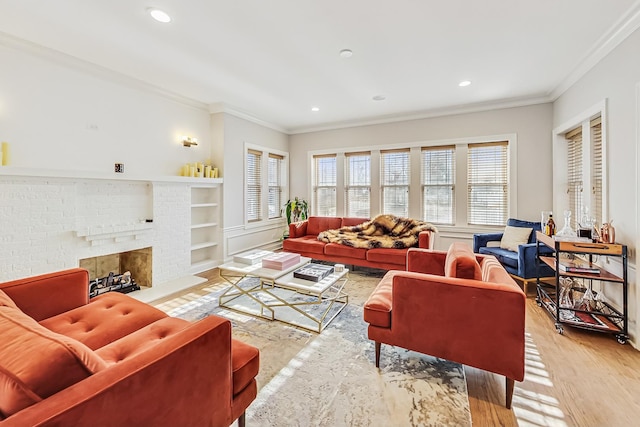 living room with crown molding, a brick fireplace, built in shelves, and light hardwood / wood-style flooring