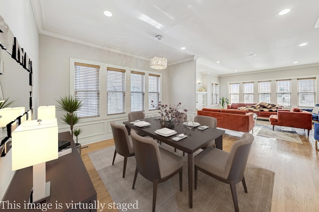 dining area with an inviting chandelier, crown molding, and light hardwood / wood-style flooring