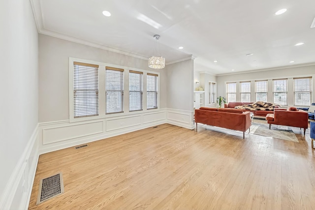 living room with ornamental molding, an inviting chandelier, and light hardwood / wood-style flooring