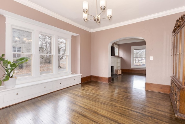 unfurnished dining area with dark wood-style floors, arched walkways, a fireplace, ornamental molding, and baseboards