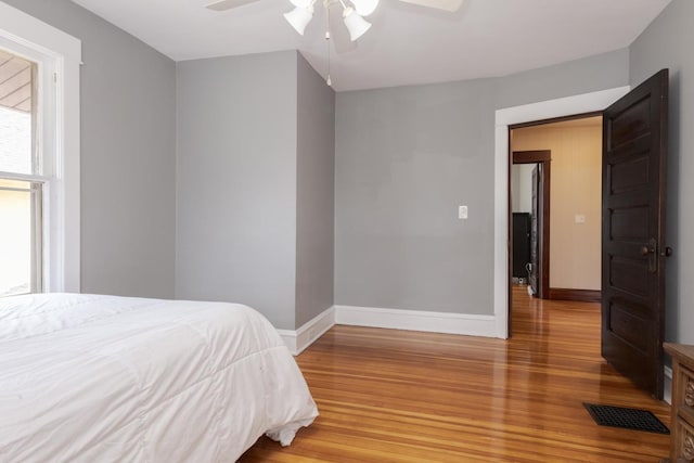 bedroom with a ceiling fan, baseboards, visible vents, and wood finished floors