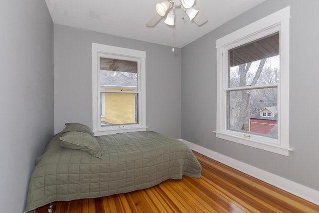 bedroom featuring wood finished floors, a ceiling fan, and baseboards