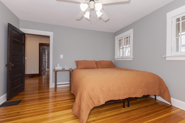 bedroom featuring visible vents, ceiling fan, baseboards, and wood finished floors