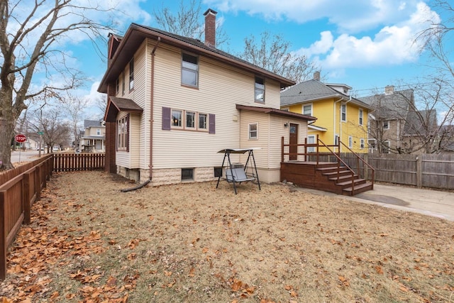 back of house featuring a fenced backyard and a chimney