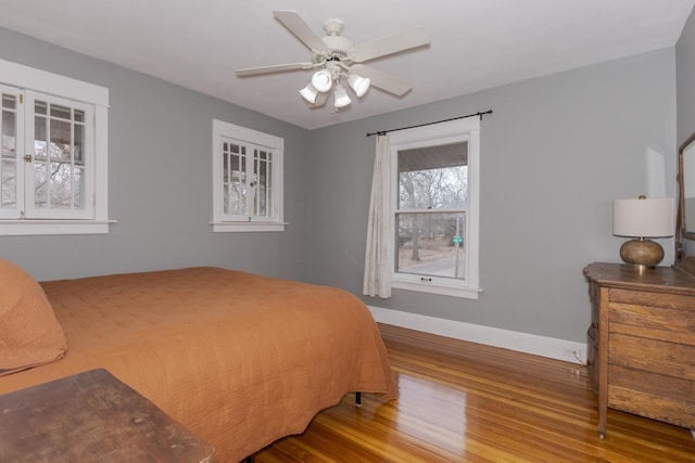 bedroom featuring ceiling fan, baseboards, and wood finished floors