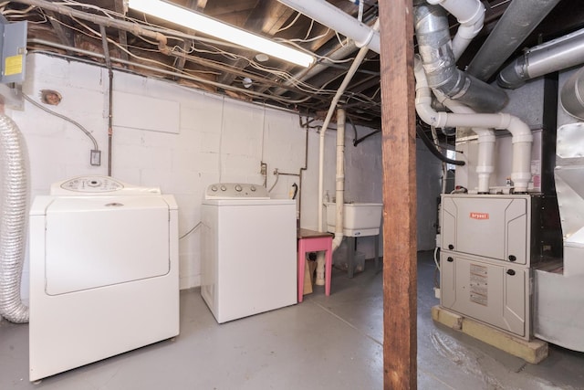 unfinished basement featuring washing machine and clothes dryer, a sink, and heating unit