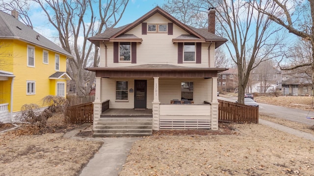 traditional style home featuring a porch, a chimney, and fence