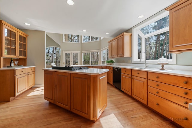 kitchen featuring light wood finished floors, light countertops, recessed lighting, glass insert cabinets, and dishwasher