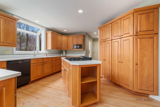 kitchen with black appliances, a sink, light wood finished floors, and light countertops