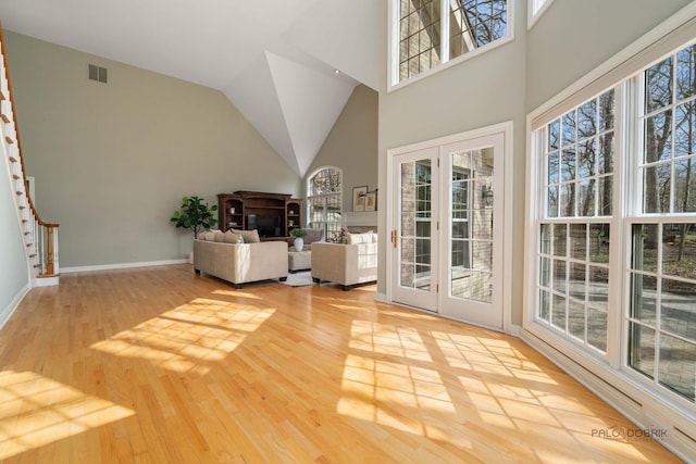 living area with stairway, a wealth of natural light, wood finished floors, and visible vents