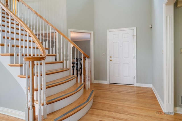 entrance foyer featuring stairway, a high ceiling, wood finished floors, arched walkways, and baseboards