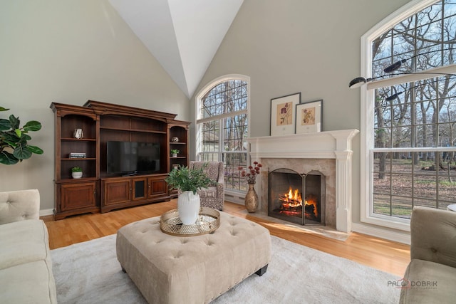 living room with light wood finished floors, high vaulted ceiling, and a high end fireplace