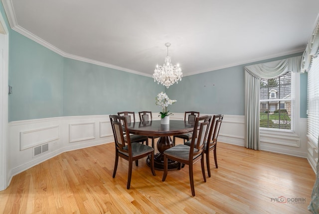 dining space with visible vents, light wood-style floors, a notable chandelier, and crown molding
