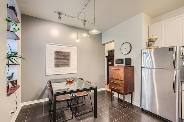 kitchen featuring white cabinetry, hanging light fixtures, rail lighting, and stainless steel refrigerator