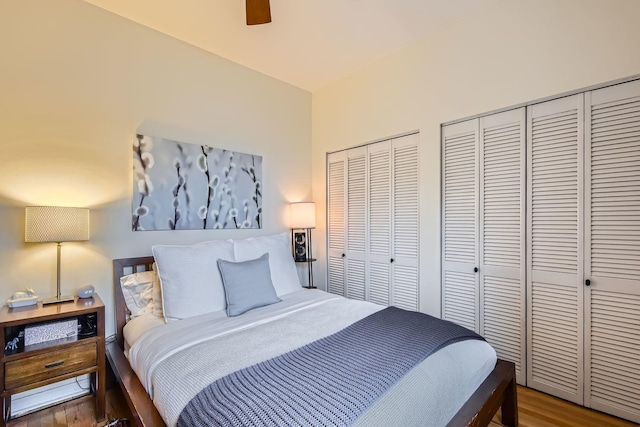 bedroom featuring two closets, wood-type flooring, and ceiling fan