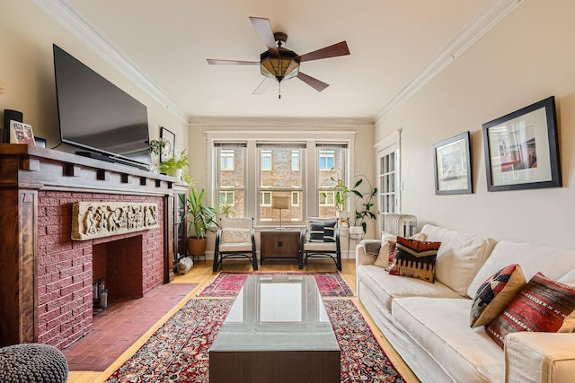 living room with a brick fireplace, ornamental molding, ceiling fan, and light wood-type flooring