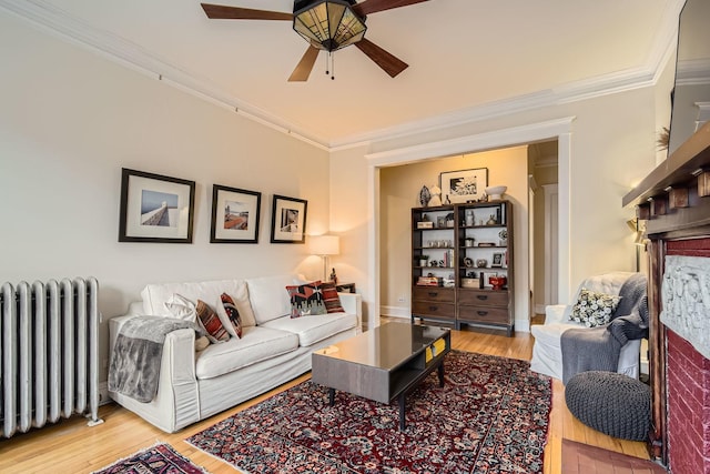 living room with crown molding, radiator, ceiling fan, and light wood-type flooring