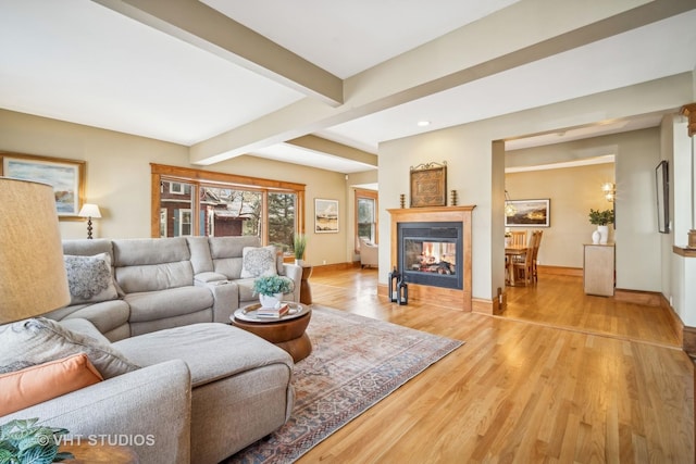 living room with beamed ceiling, a multi sided fireplace, and light hardwood / wood-style floors