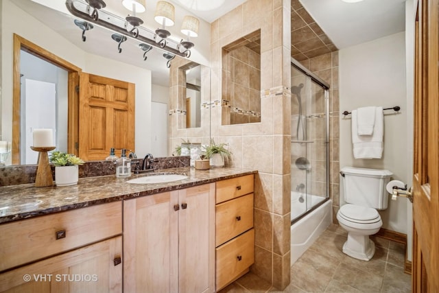 full bathroom featuring vanity, tile patterned flooring, toilet, and combined bath / shower with glass door