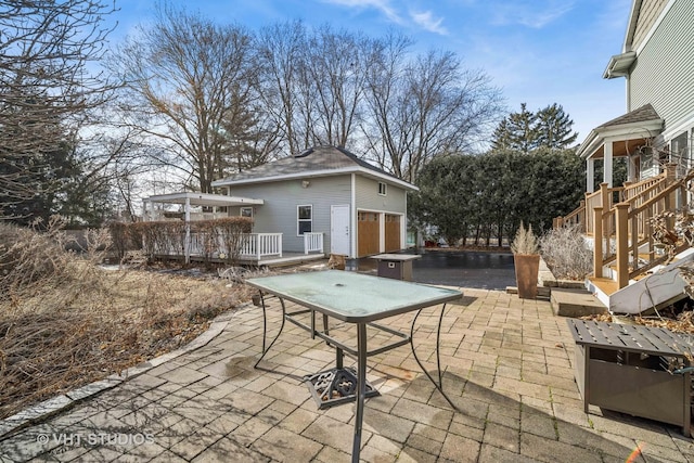 view of patio featuring a garage, a wooden deck, and an outdoor structure