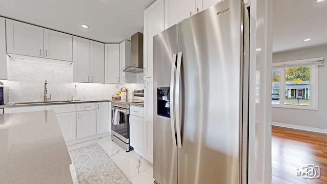 kitchen featuring white cabinetry, wall chimney range hood, stainless steel appliances, and sink