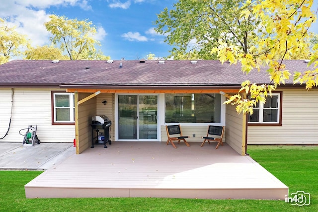 rear view of property with a deck and a lawn