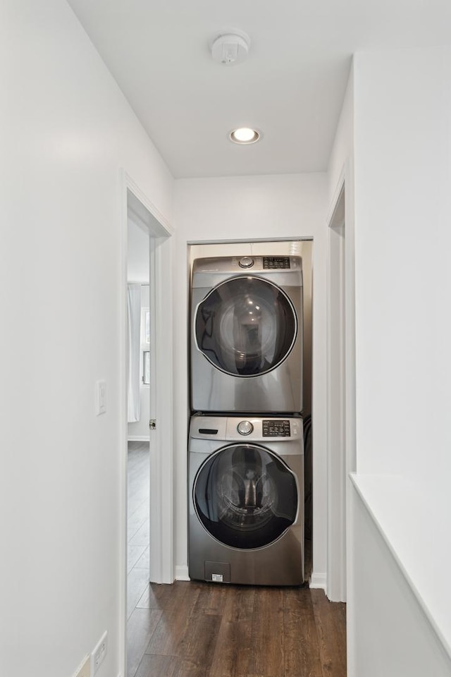 clothes washing area featuring stacked washer and clothes dryer and dark hardwood / wood-style floors