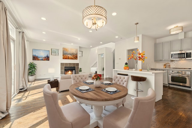 dining area with dark wood-type flooring, a tile fireplace, and a chandelier