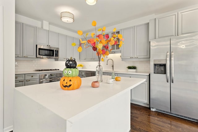 kitchen with sink, decorative backsplash, stainless steel appliances, and a center island with sink