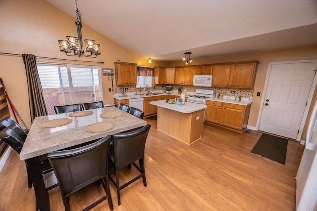 kitchen featuring a center island, light countertops, an inviting chandelier, light wood-style floors, and white appliances