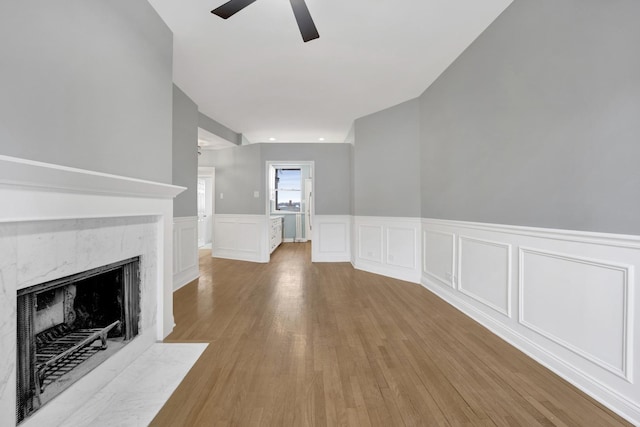 unfurnished living room with ceiling fan, a fireplace, and light hardwood / wood-style flooring