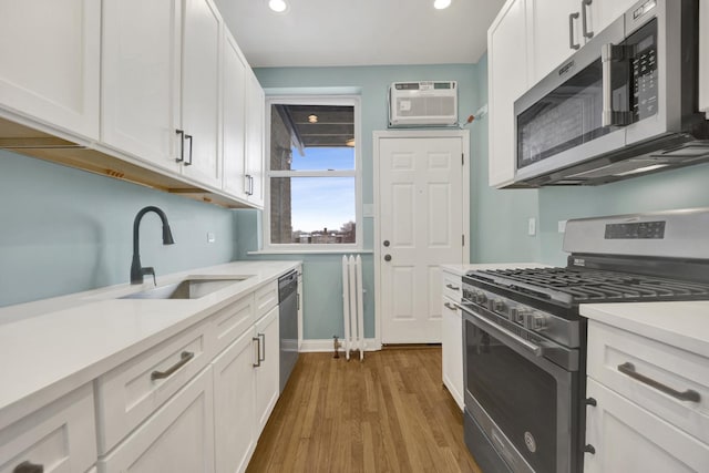 kitchen with sink, white cabinetry, appliances with stainless steel finishes, dark hardwood / wood-style flooring, and a wall unit AC