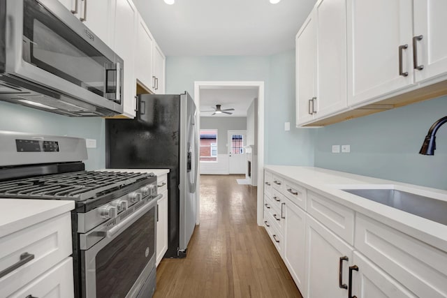 kitchen featuring white cabinetry, appliances with stainless steel finishes, dark hardwood / wood-style flooring, and sink