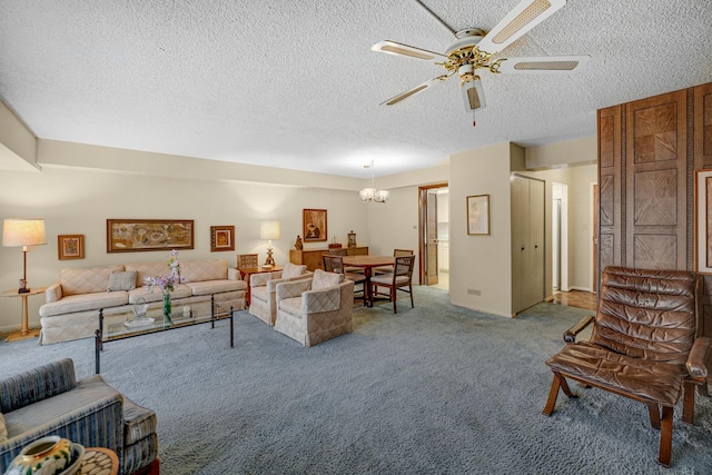 living room featuring carpet flooring, ceiling fan with notable chandelier, and a textured ceiling