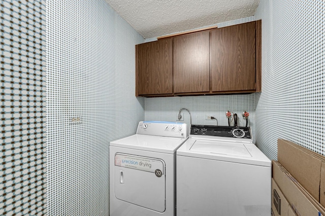 washroom featuring cabinets, washing machine and clothes dryer, and a textured ceiling